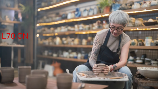 陶艺工作室里，一位老年女性匠人在陶轮上制作陶碗